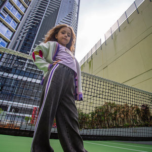 girls wide leg pants in black with sporty side purple/pink/white tape detail by Little Baddie, trendy tween streetwear outfit , girl standing tall in front of high riser