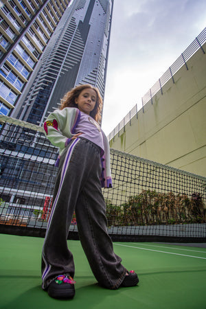 girls wide leg pants in black with sporty side purple/pink/white tape detail by Little Baddie, trendy tween streetwear outfit , girl standing tall in front of high riser