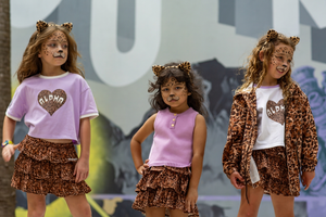 Girls wearing Little Baddie leopard ruffle skirts, Untamed Heart tees and Untamed Leopard Jacket, styled for Halloween with leopard face paint and ears