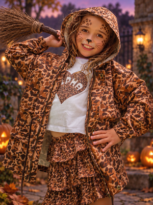 Girl in hooded Untamed leopard jacket, white ALPHA heart tee and leopard ruffle skirt with leopard face paint, holding a broom among Halloween pumpkins – Little Baddie